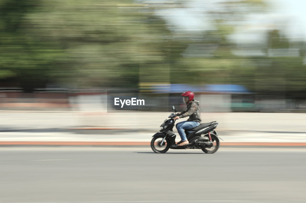 SIDE VIEW OF A MAN RIDING MOTORCYCLE ON ROAD