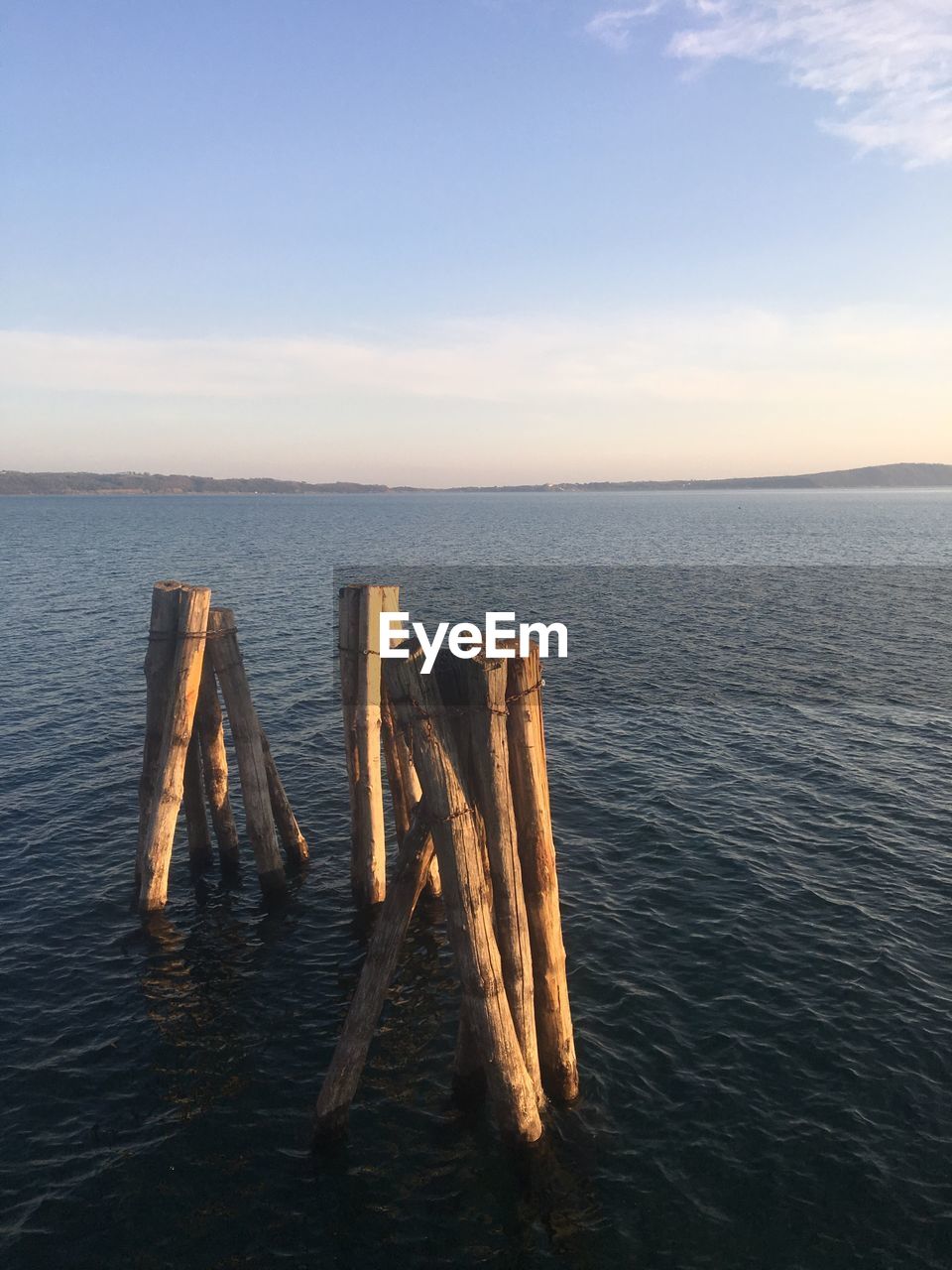 Wooden posts in sea against sky