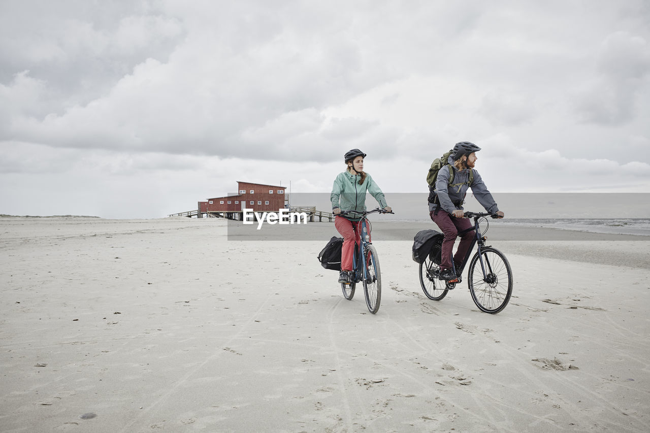 Germany, schleswig-holstein, st peter-ording, couple riding bicycle on the beach