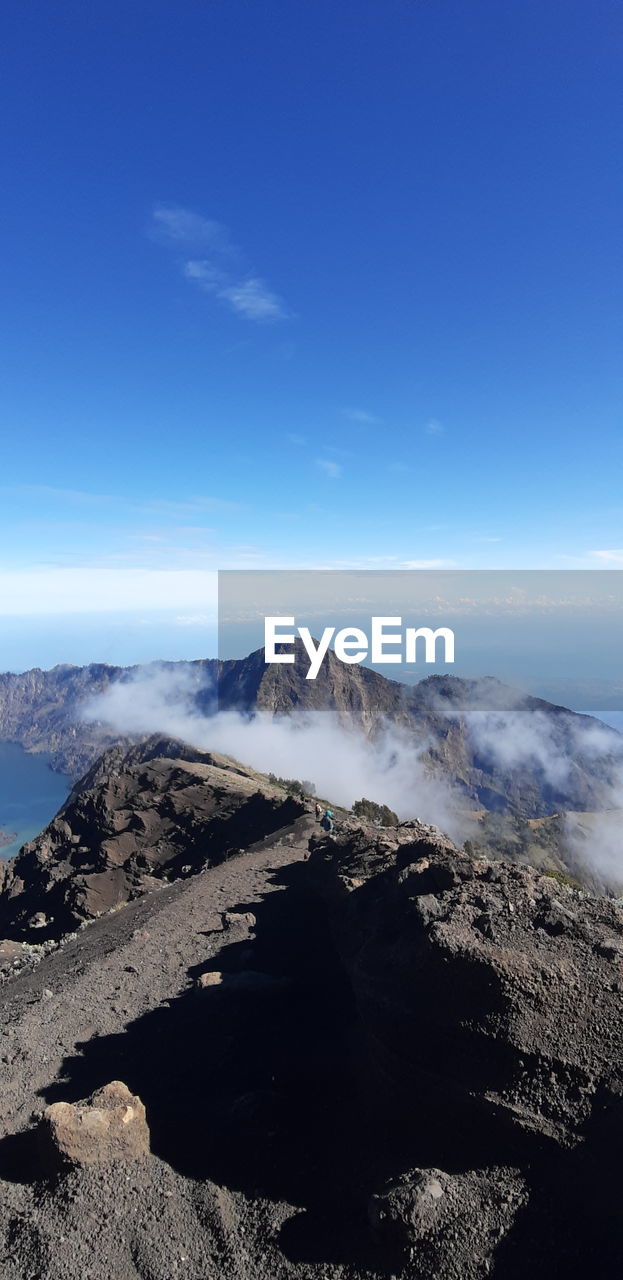 Scenic view of volcanic mountain against blue sky