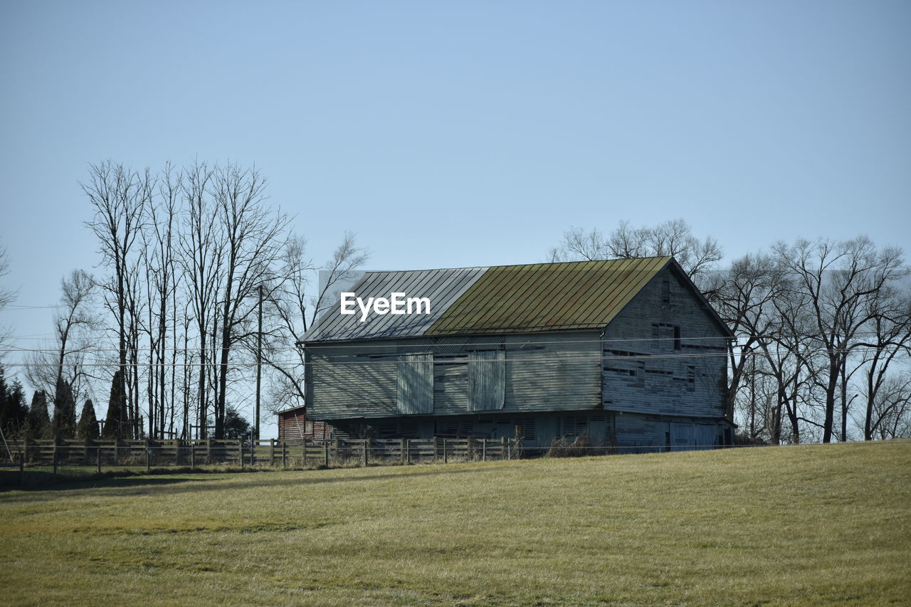 HOUSE BY FIELD AGAINST CLEAR SKY