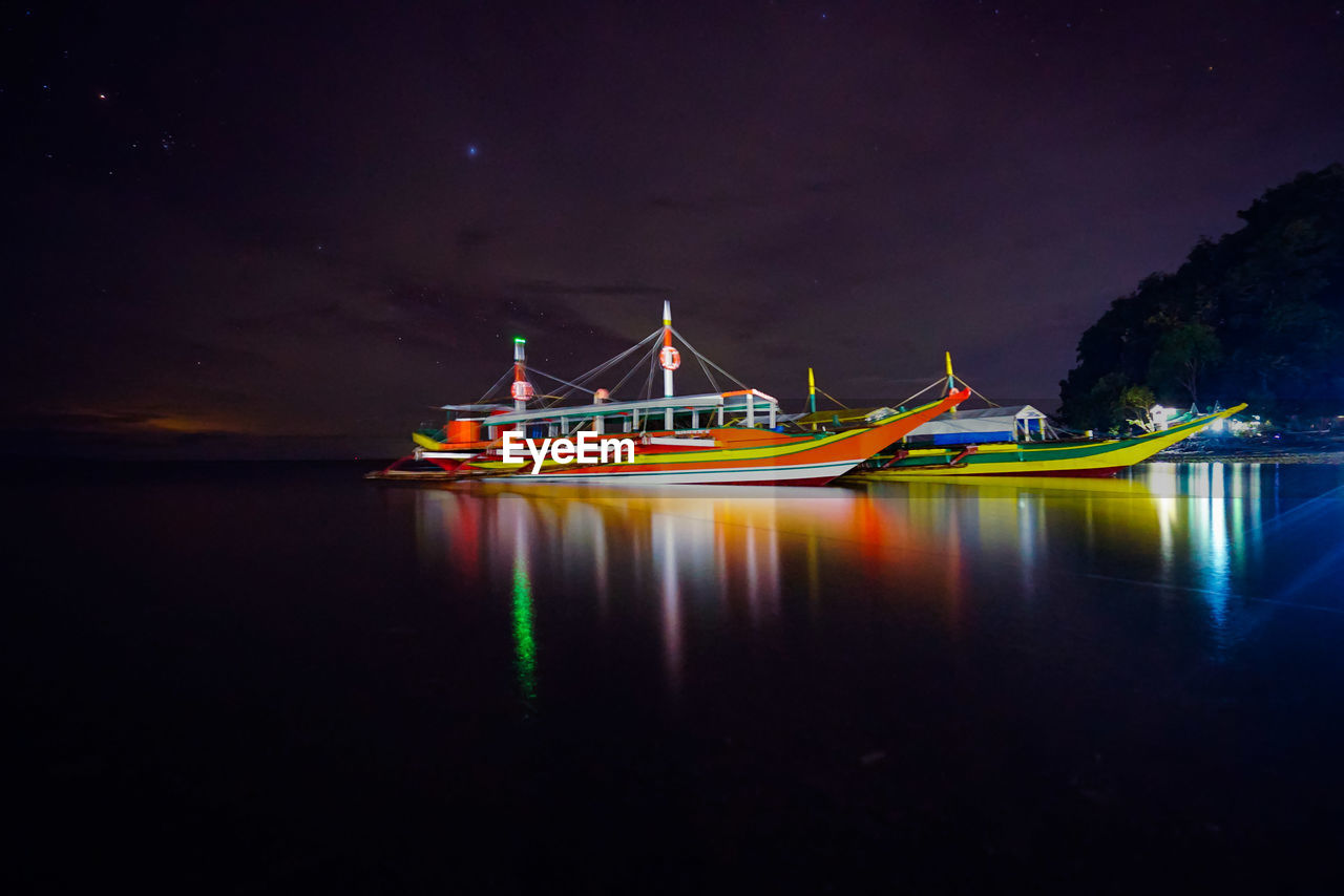 Boat moored in lake against sky at night