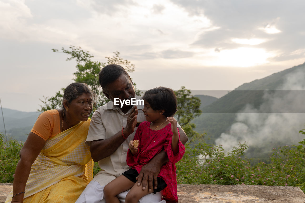 side view of mother and daughter sitting on mountain