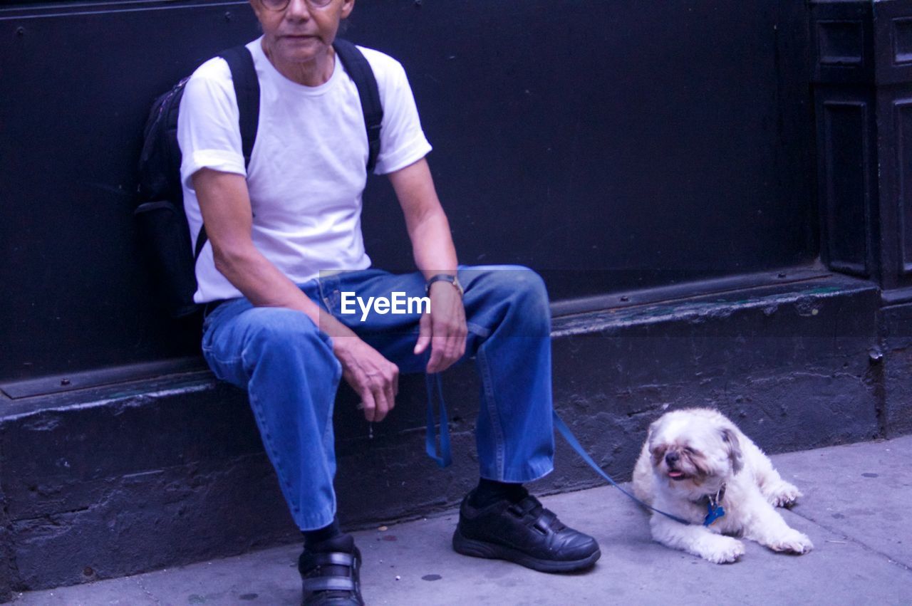 LOW SECTION OF MAN WALKING WITH DOG ON STREET