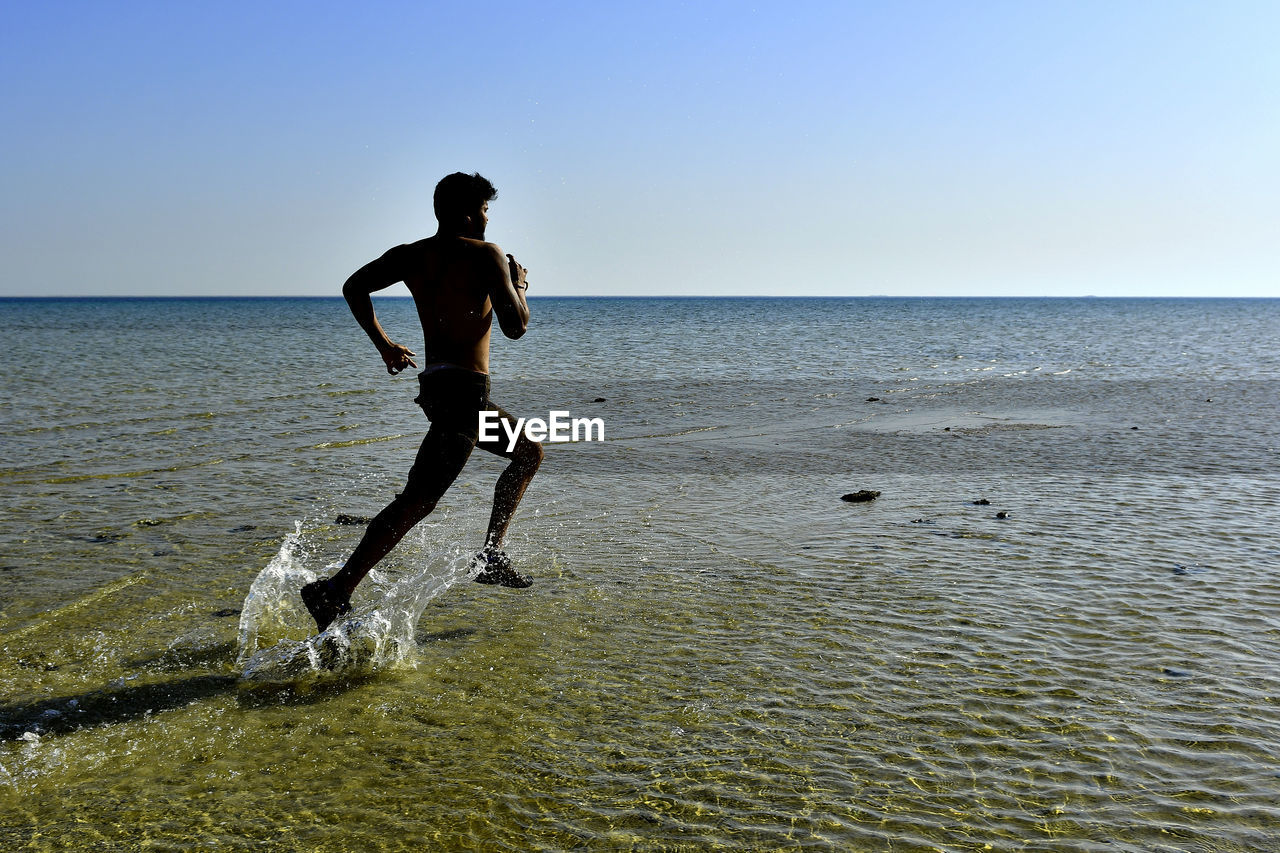 Man running on beach against sky