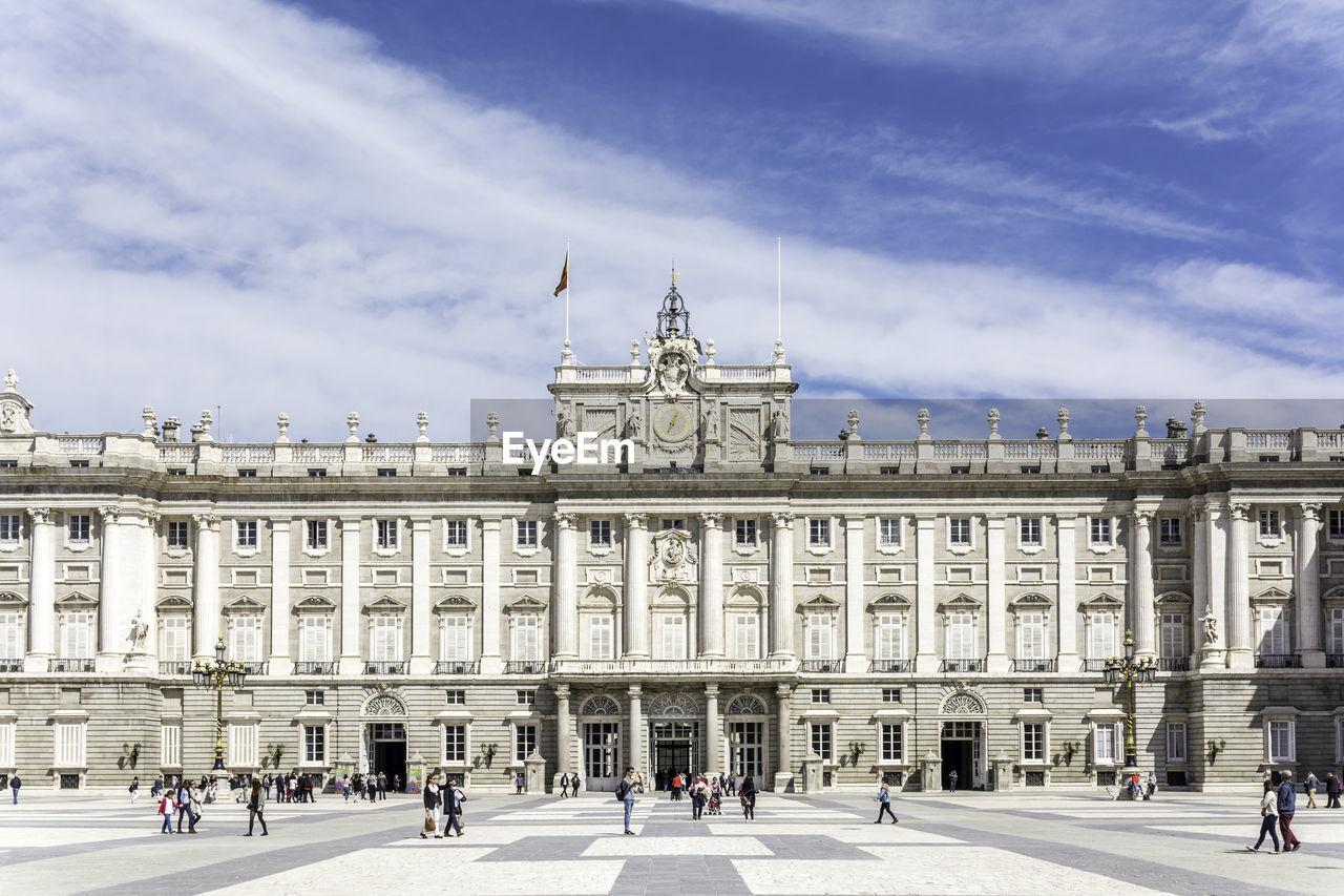 Tourists visiting royal palace of madrid against sky