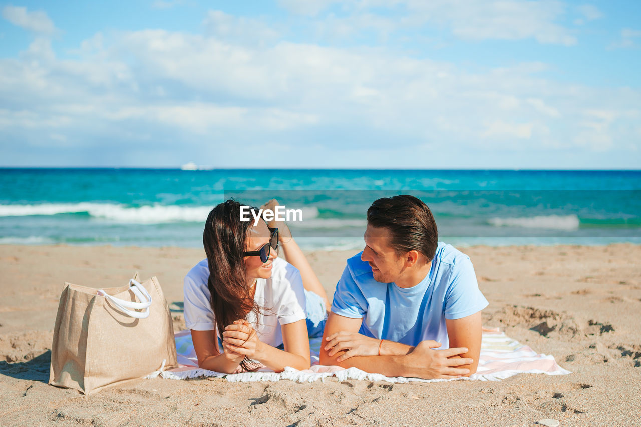 rear view of woman sitting on beach against sky