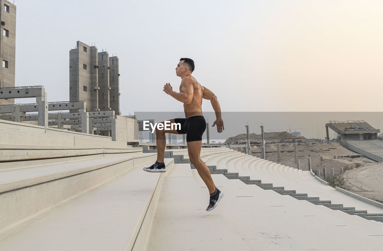 Muscular shirtless man exercising outdoors