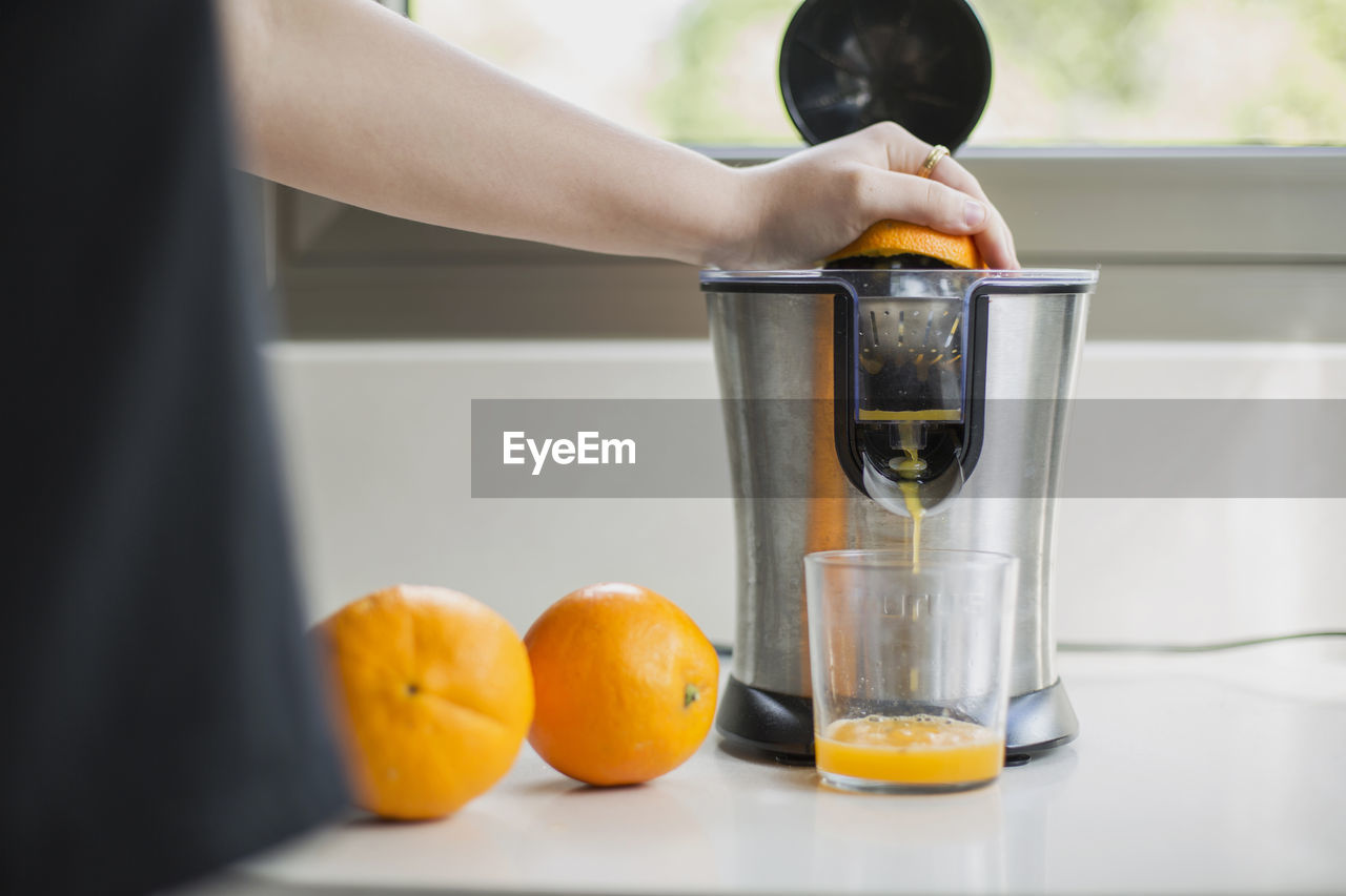 Midsection of man preparing orange juice in kitchen