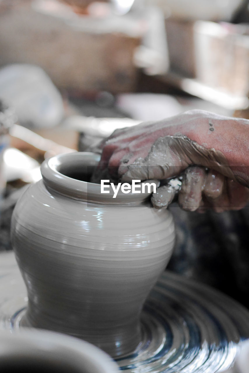Midsection of man working on pottery wheel