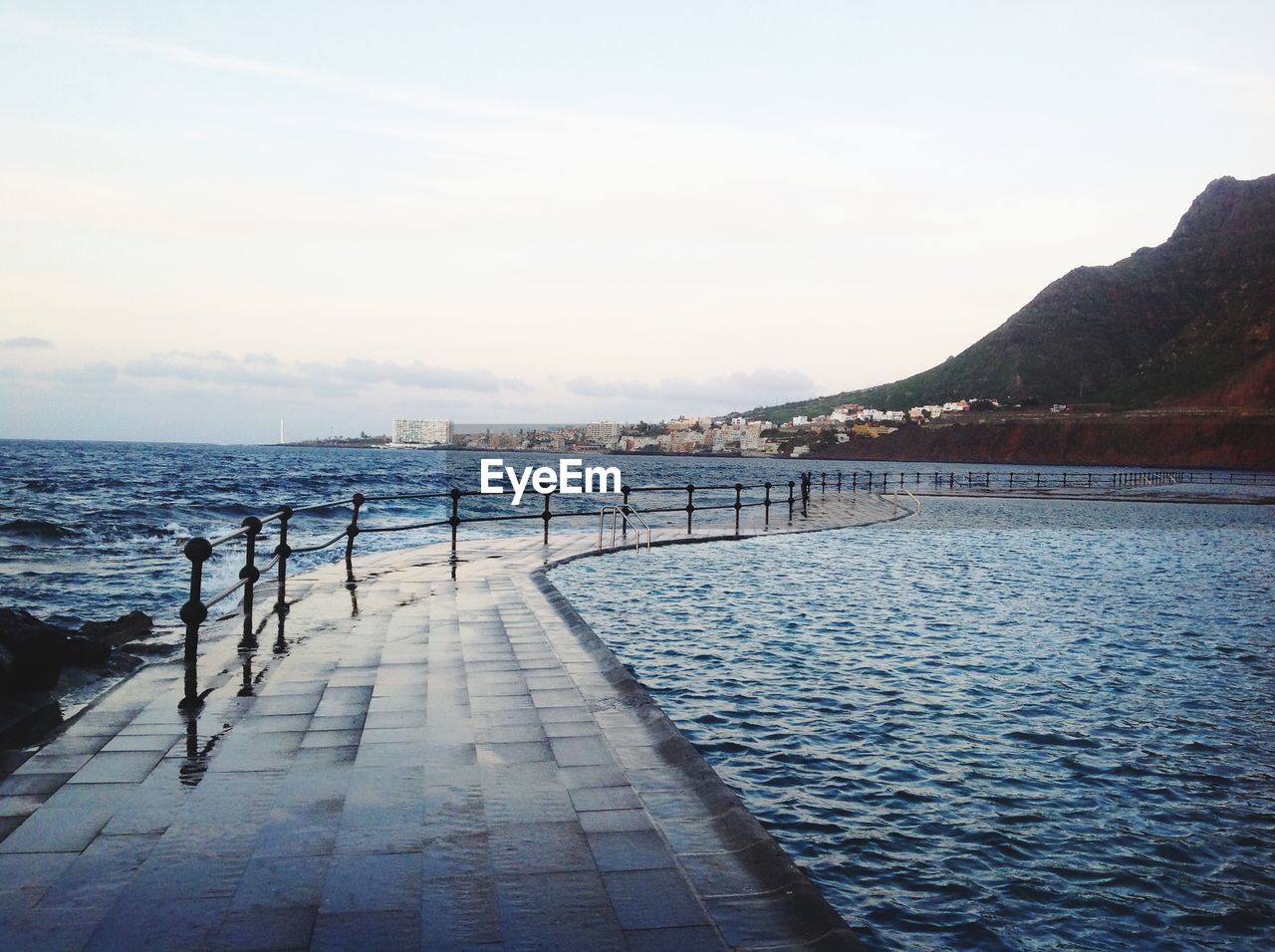 Walkway in sea against sky