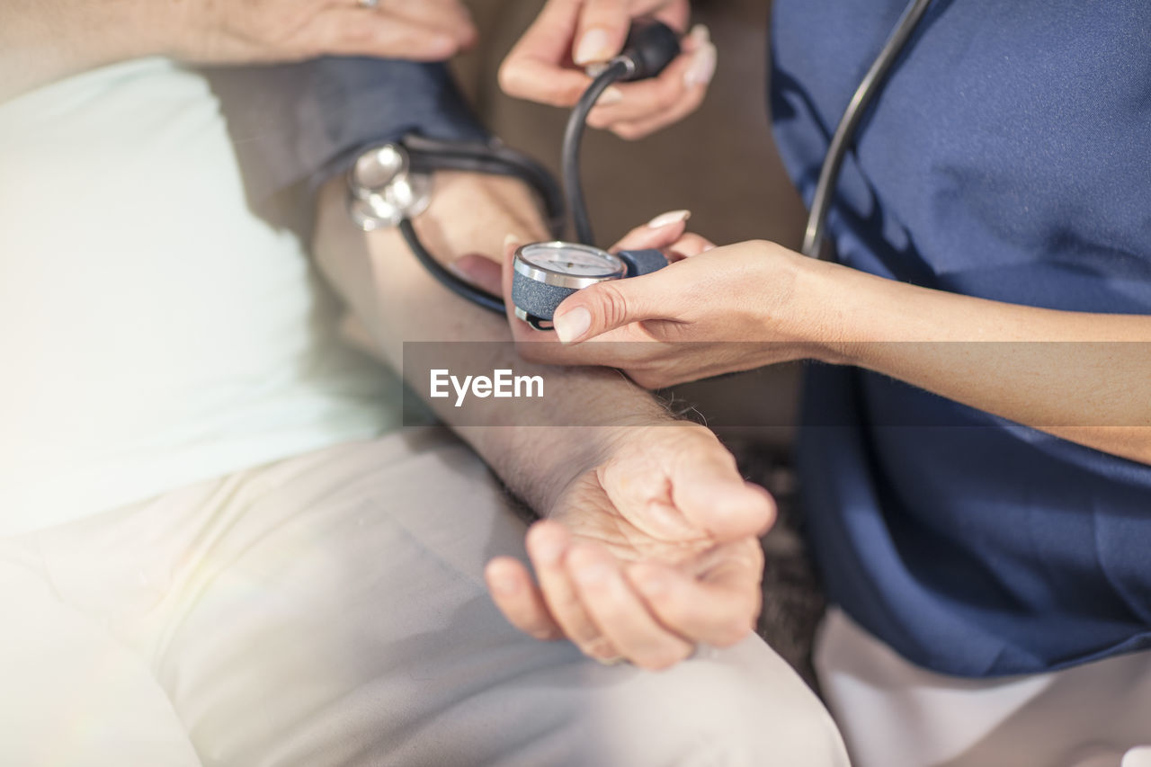 Nurse taking blood pressure of senior patient at home