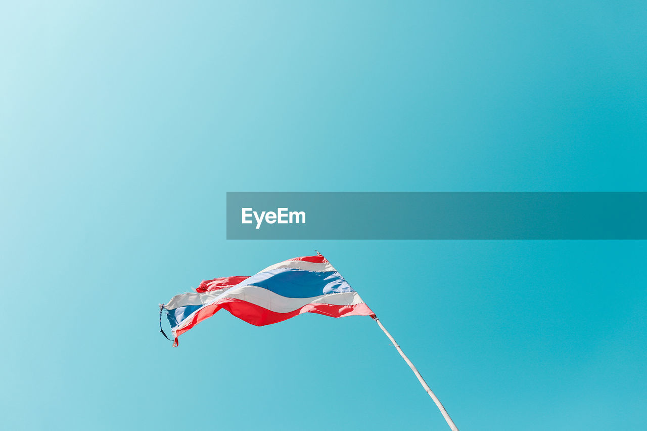 Low angle view of flag against clear blue sky