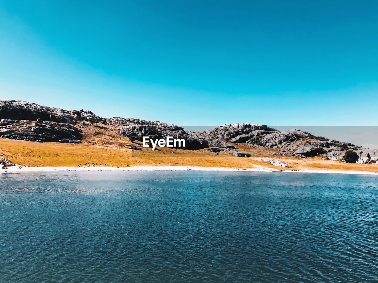 Scenic view of lake against clear blue sky