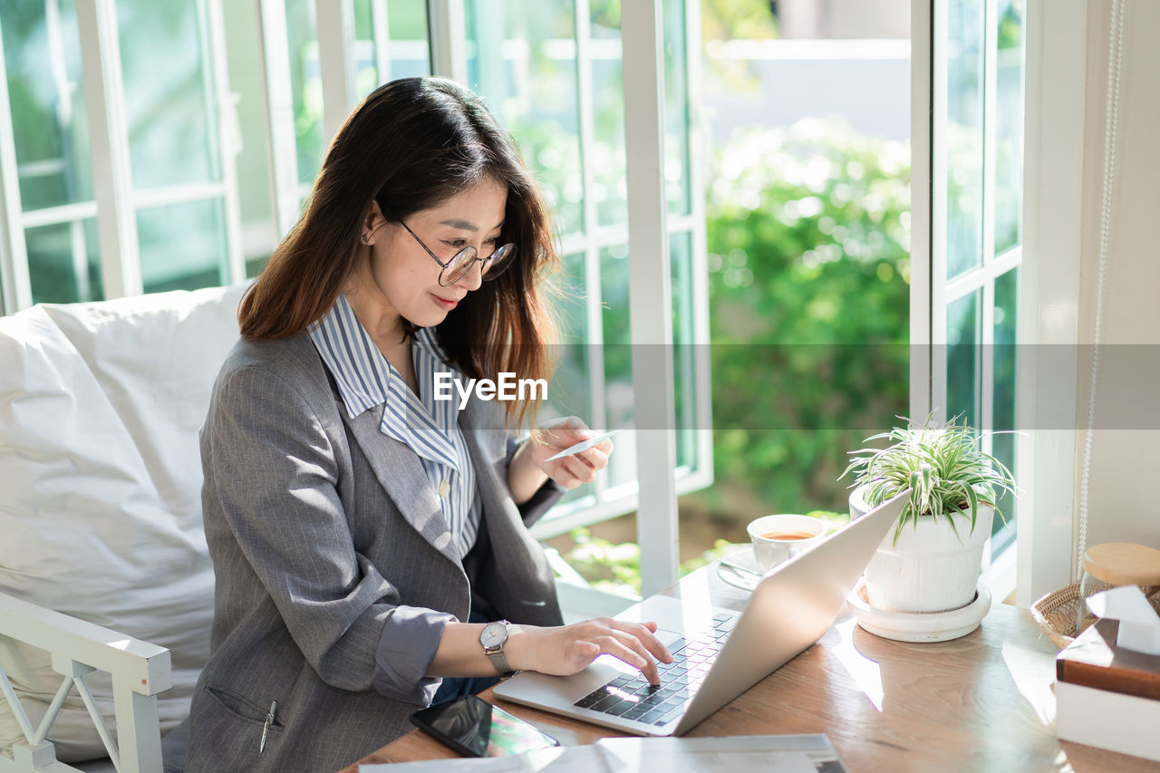 Young woman using phone while sitting on table