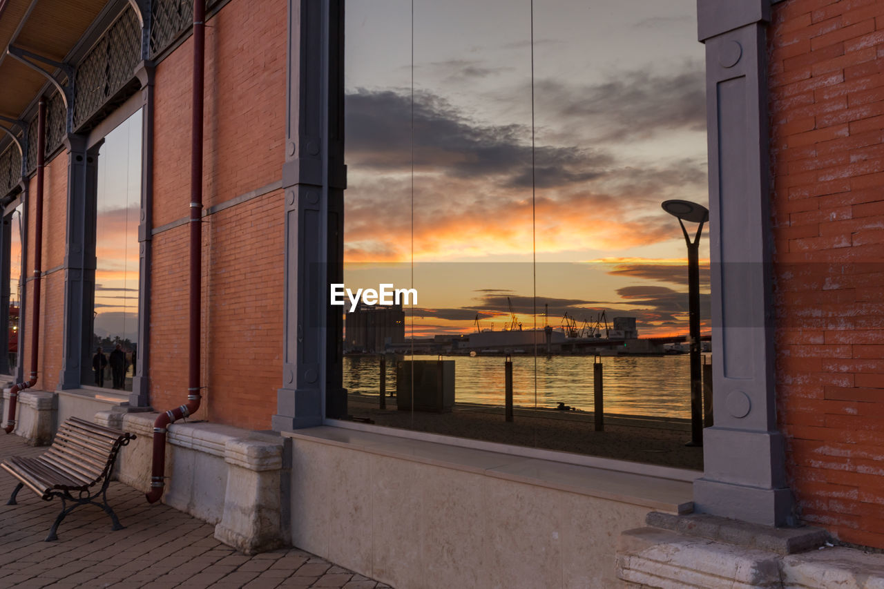 Buildings against sky during sunset seen through window