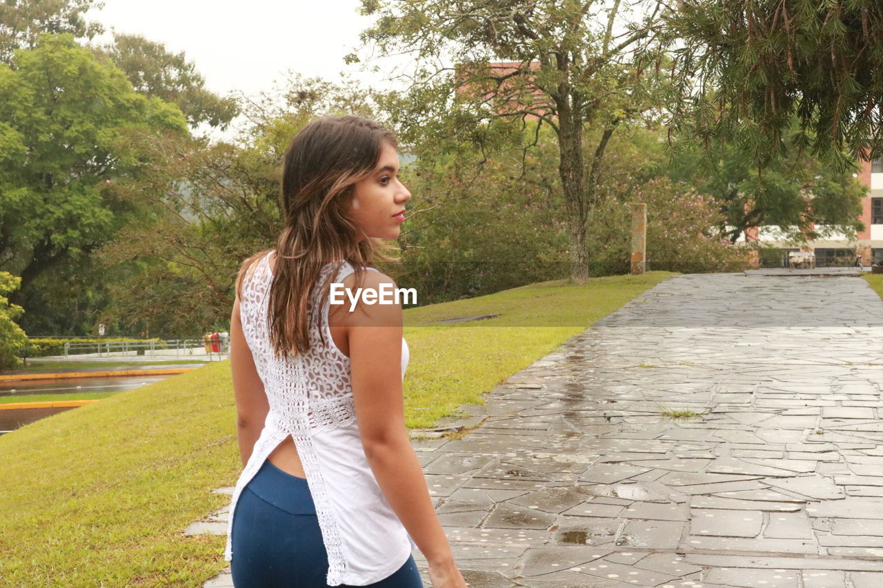 Rear view of young woman walking on footpath in public park