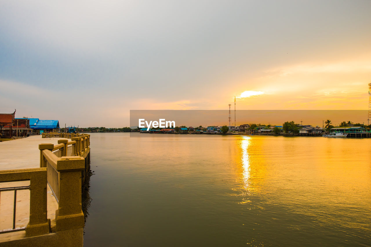 SCENIC VIEW OF LAKE BY BUILDING AGAINST SKY DURING SUNSET