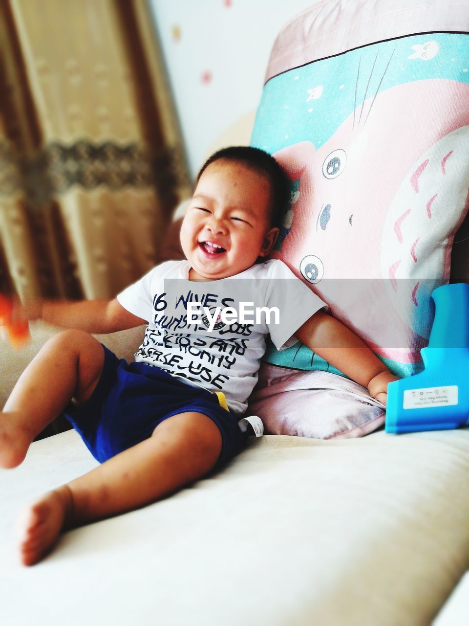 PORTRAIT OF HAPPY BOY PLAYING WITH BABY SITTING AT HOME