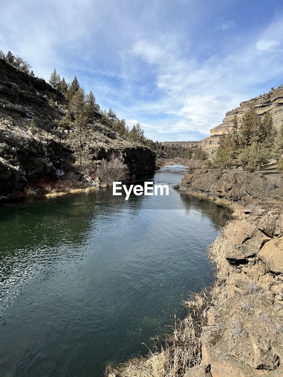 reflection, water, nature, cliff, terrain, rock, sea, coast, beauty in nature, sky, scenics - nature, day, no people, cloud, outdoors, land, wave, tranquility, sunlight, environment, non-urban scene, tree, ocean, geology, rock formation, plant, beach, blue, cave