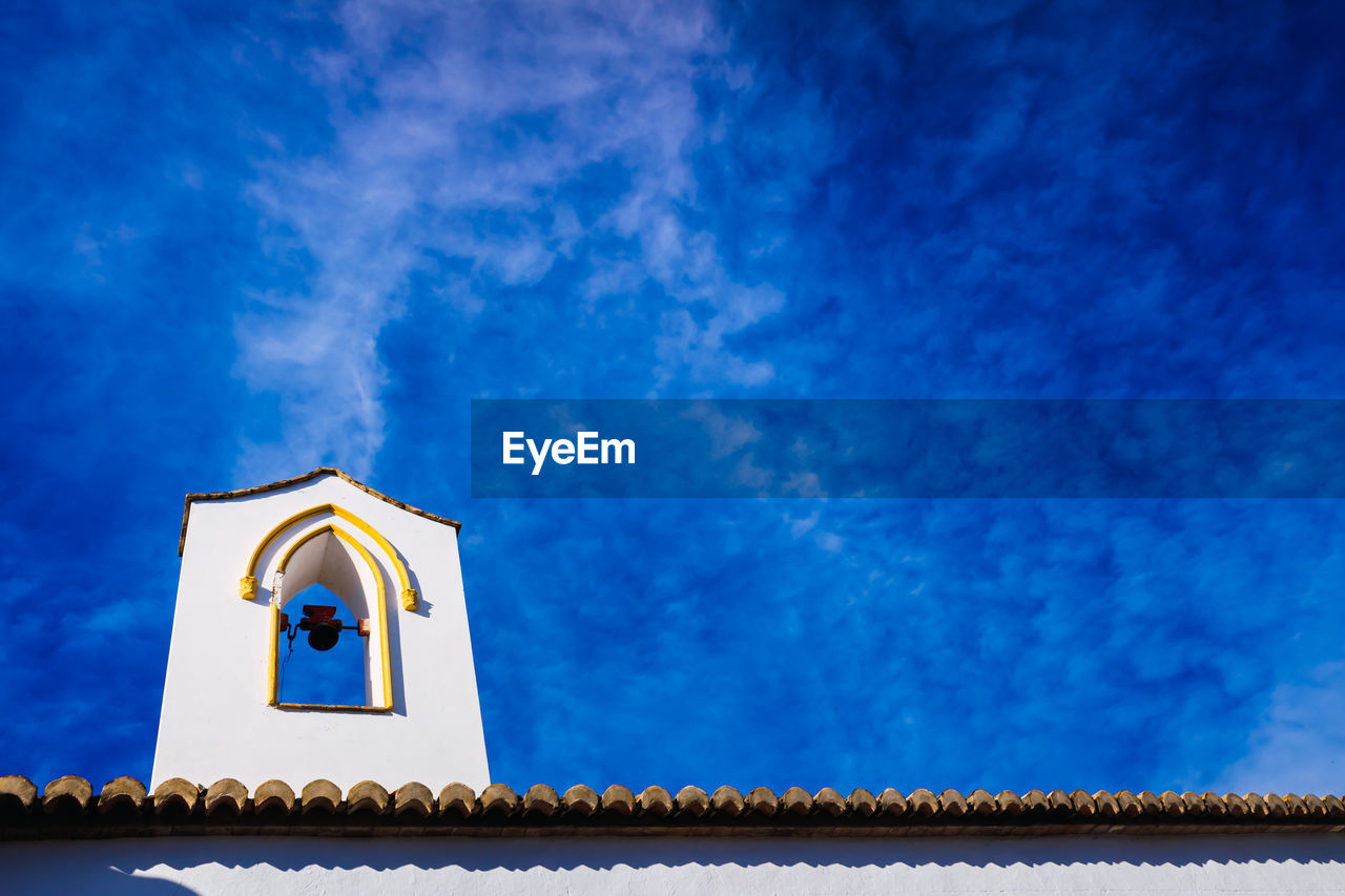 Low angle view of bell tower against blue sky