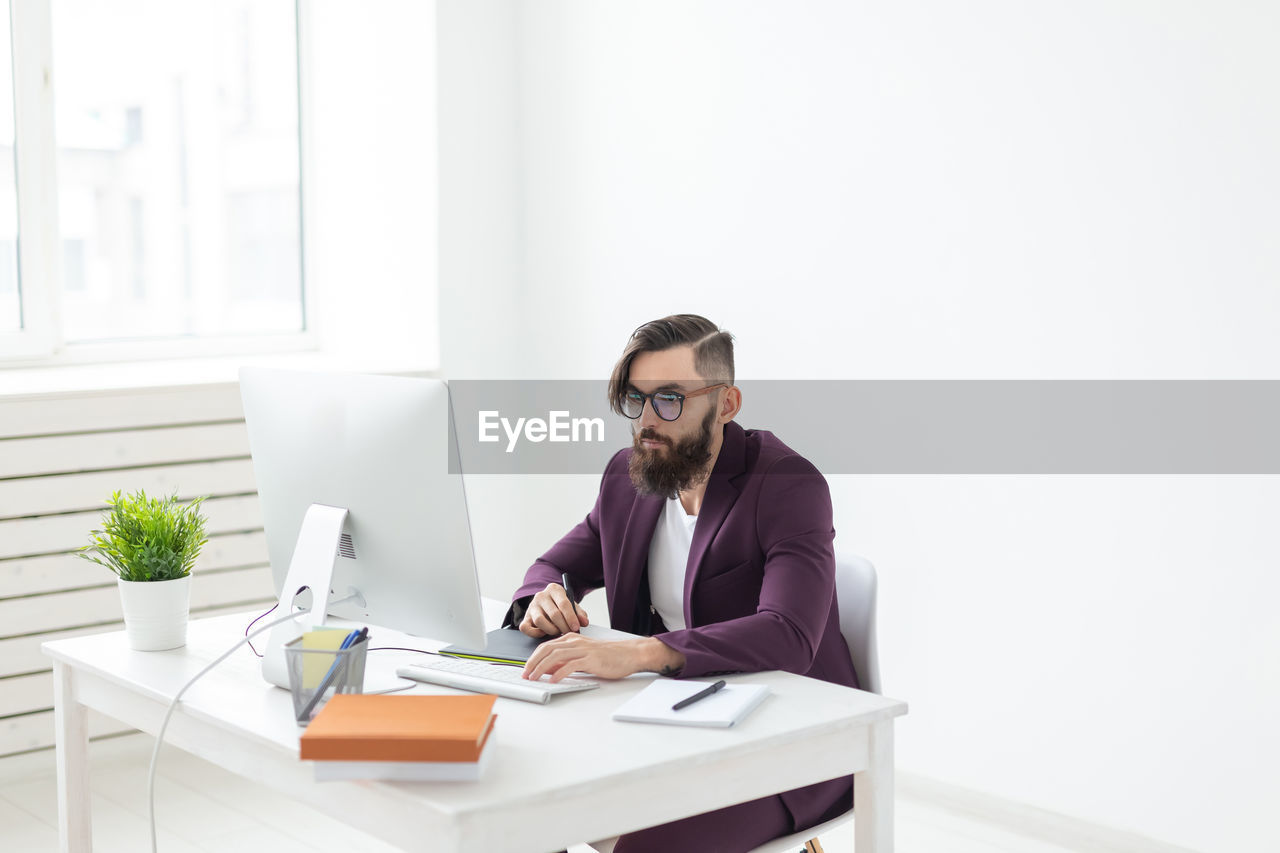 Young man using mobile phone while sitting on table