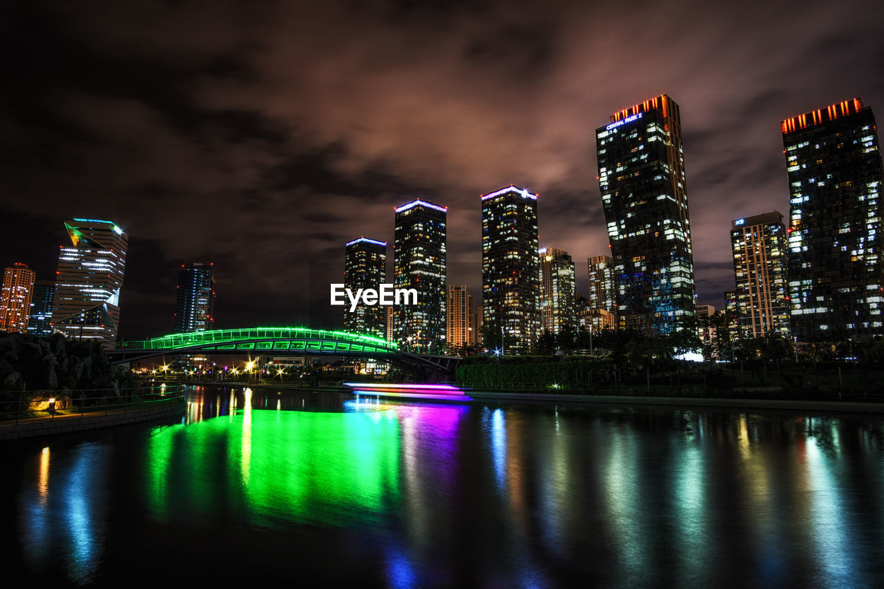 Illuminated buildings by river at night