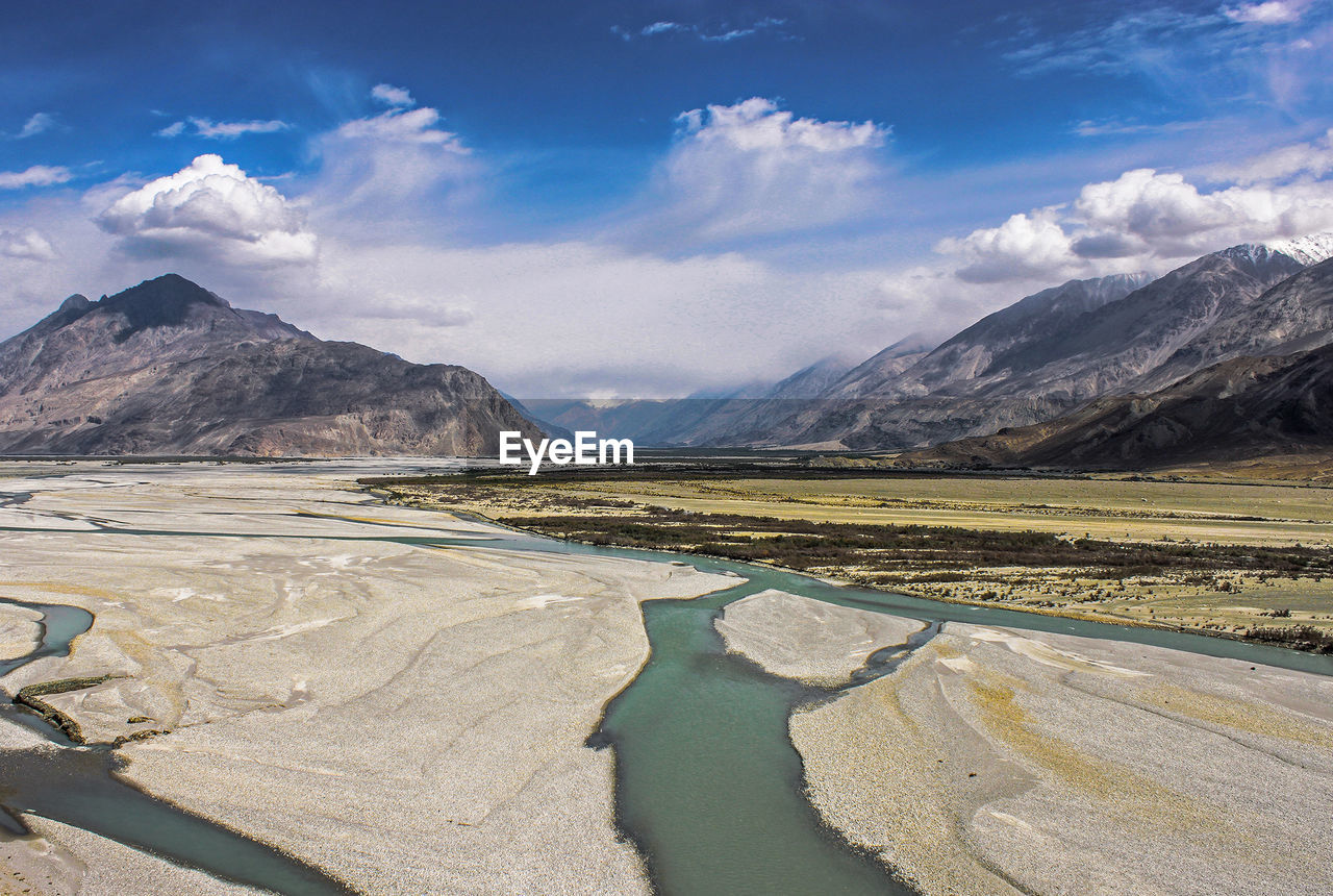 Scenic view of river and mountains against cloudy sky