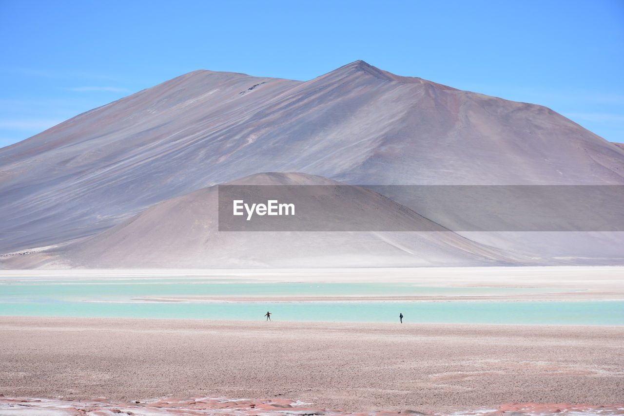 Scenic view of sea by mountains against sky