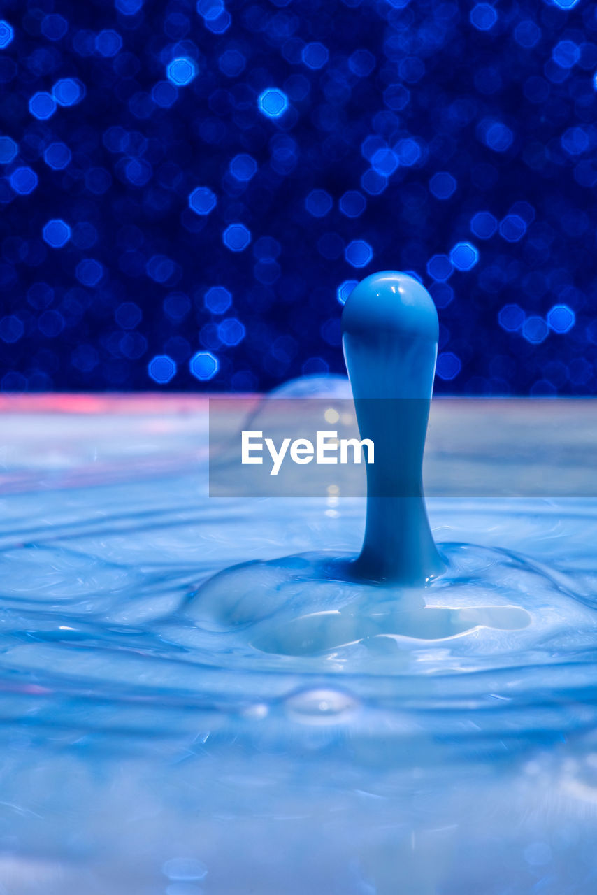 CLOSE-UP OF WATER SPLASHING ON BLUE SURFACE