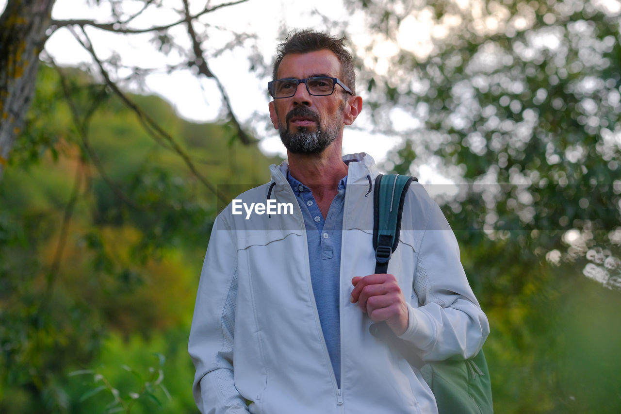 Portrait of young man standing against plants