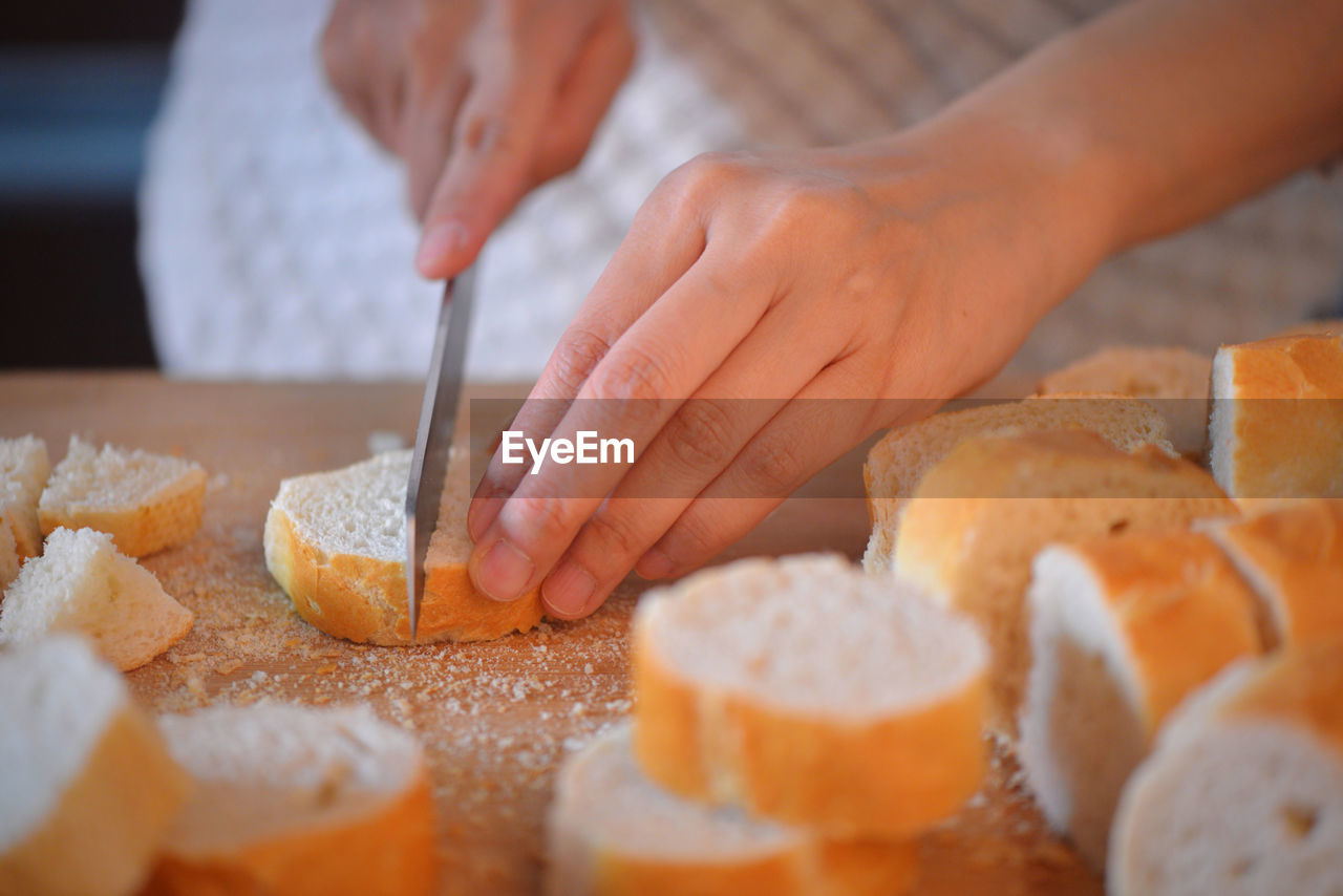 Midsection of woman cutting bread on table