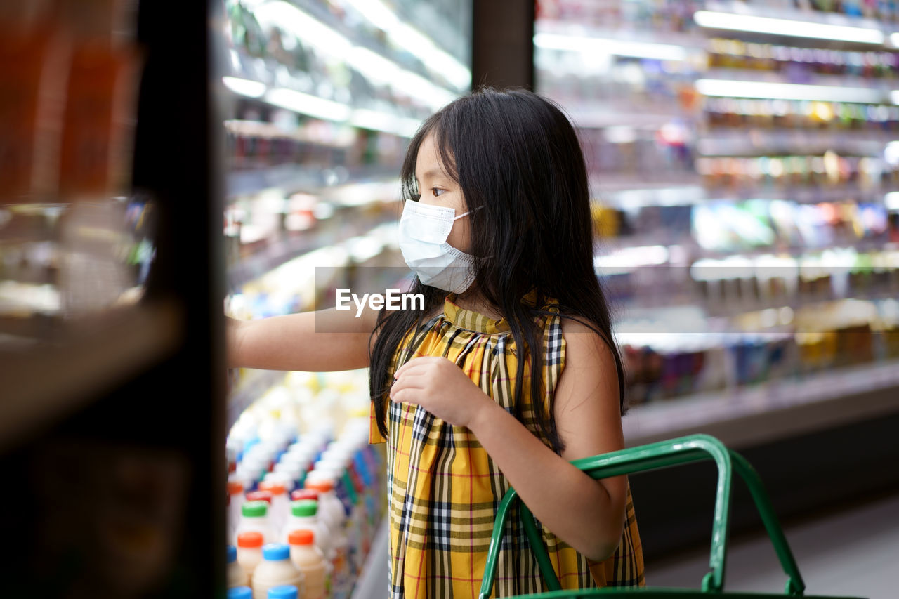 Cute girl wearing mask shopping at supermarket