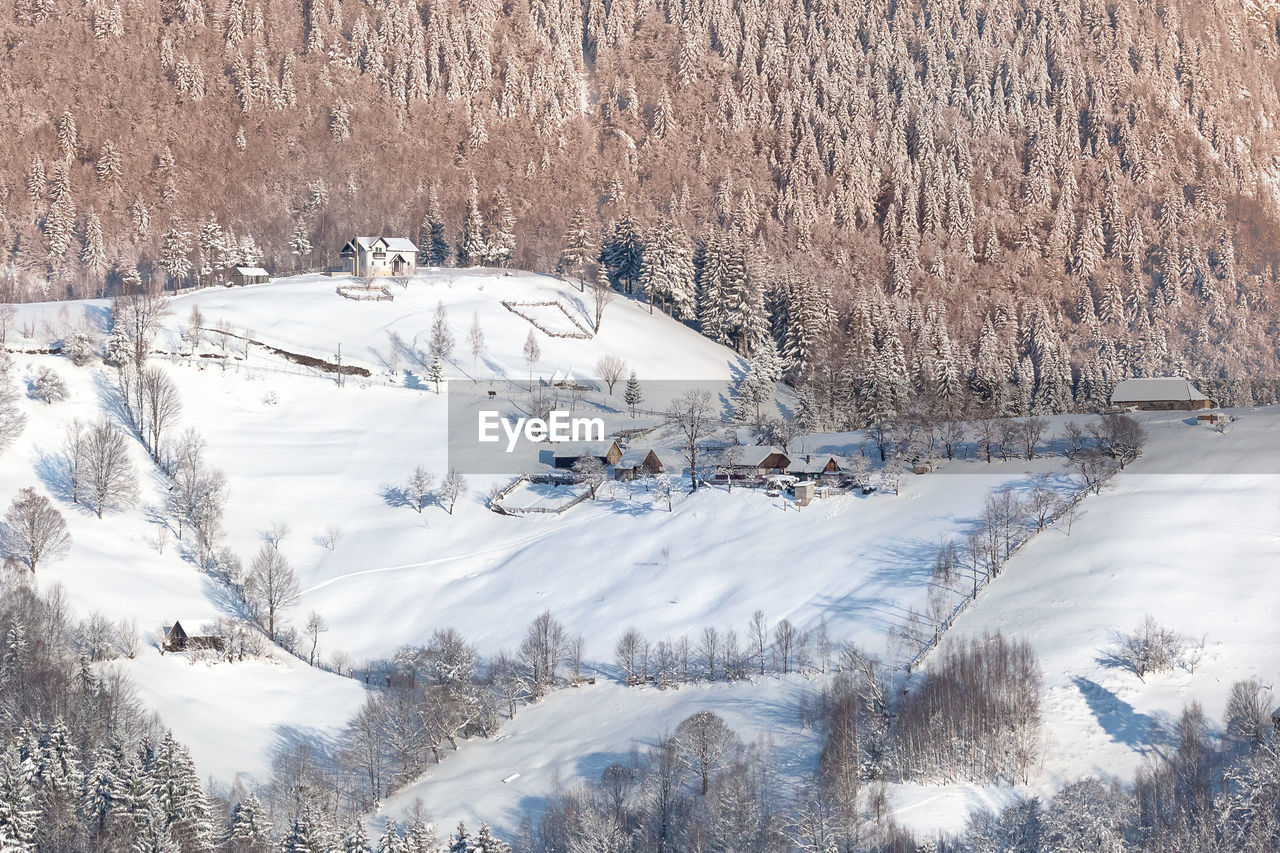 High angle view of snow covered hill with fences and trees 