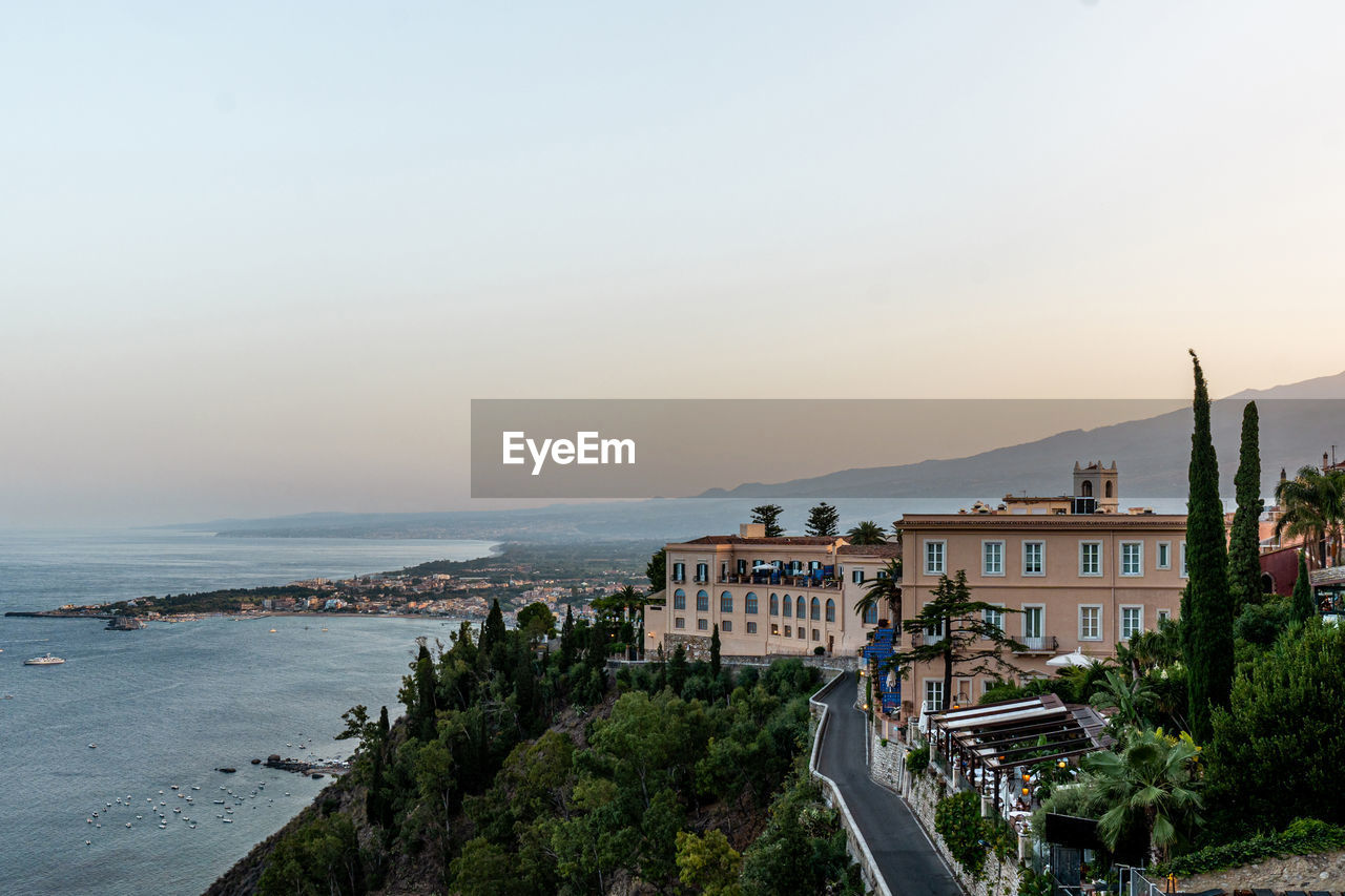 Hotel building in taormina with accommodation for tourists near coast at sunset