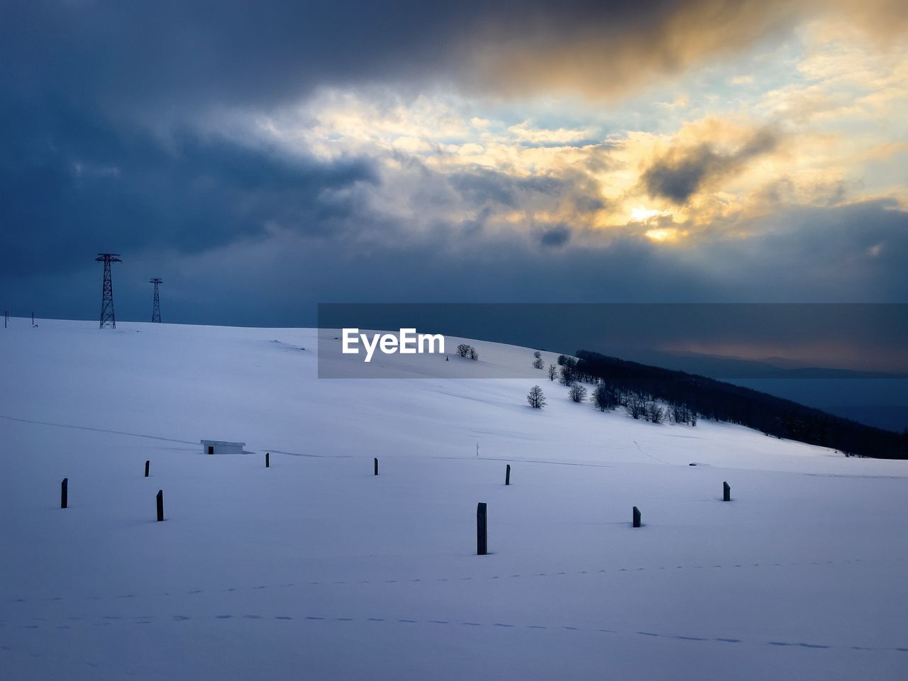 Transmission towers in the mountains during winter on a cloudy day