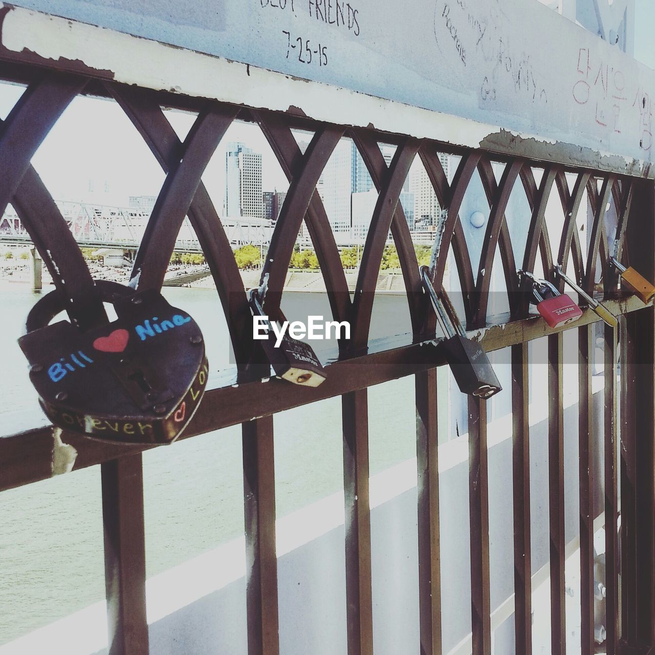 Close-up of padlocks on metallic railing over bridge