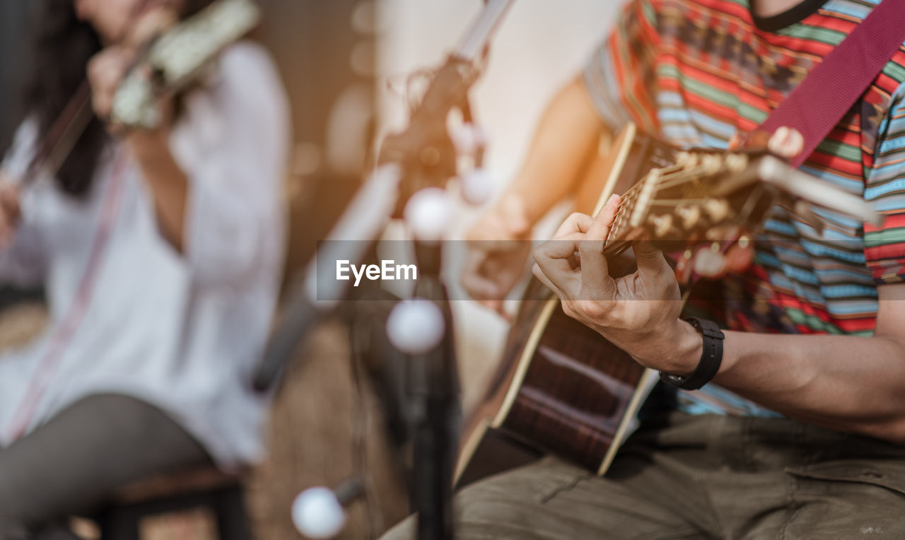 Midsection of man playing guitar at music concert