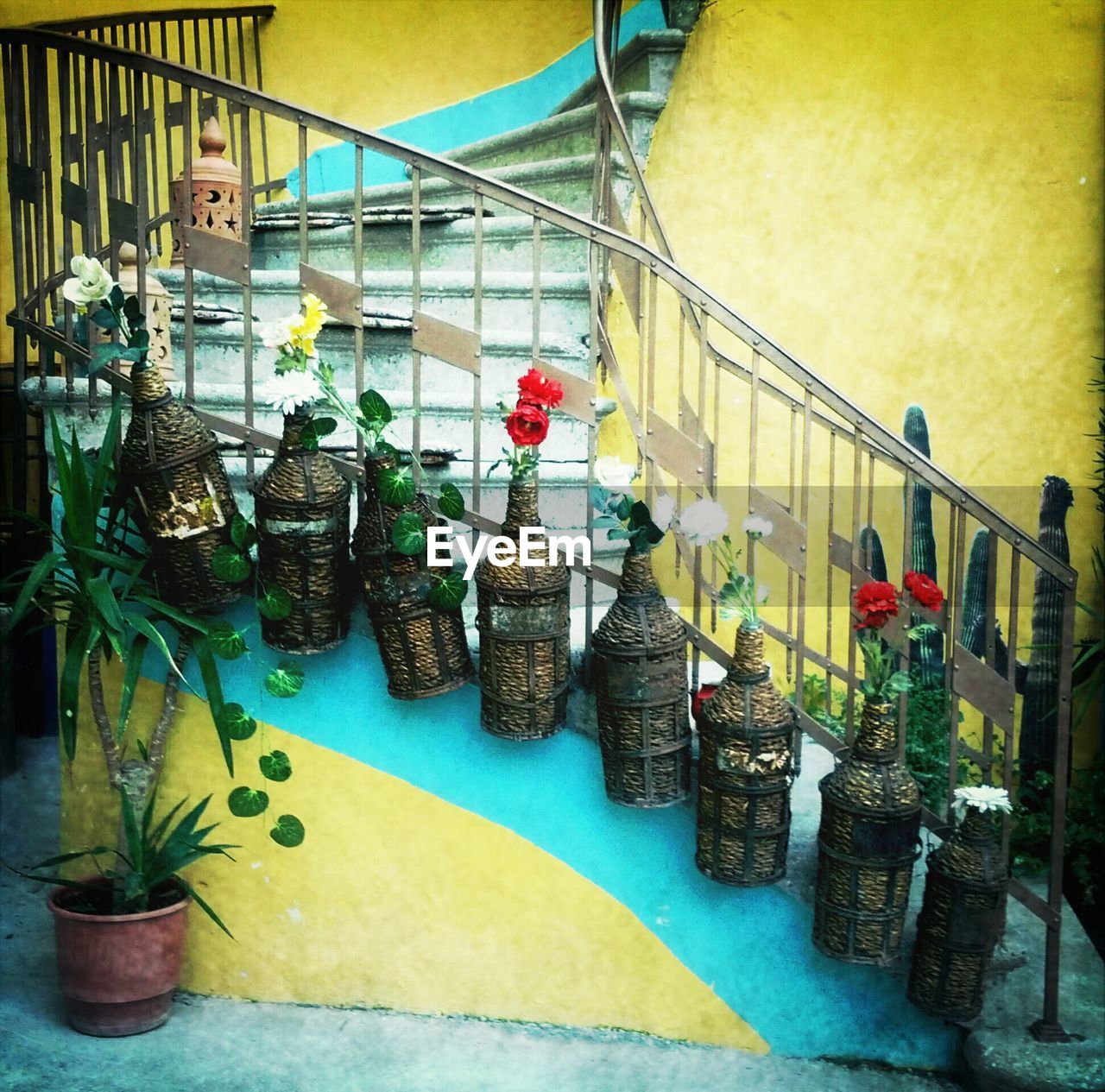 Flowers in bottles hanging on railing