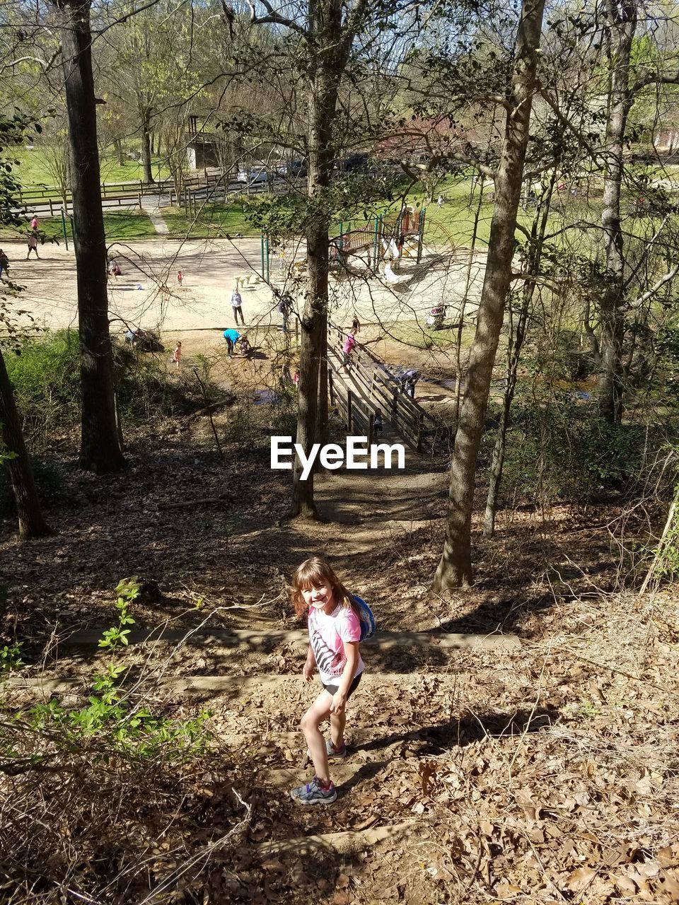 GIRL STANDING ON TREE TRUNK