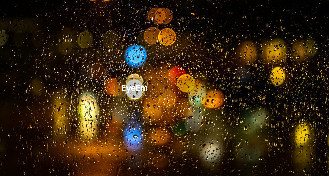 FULL FRAME SHOT OF WET GLASS WINDOW AT NIGHT