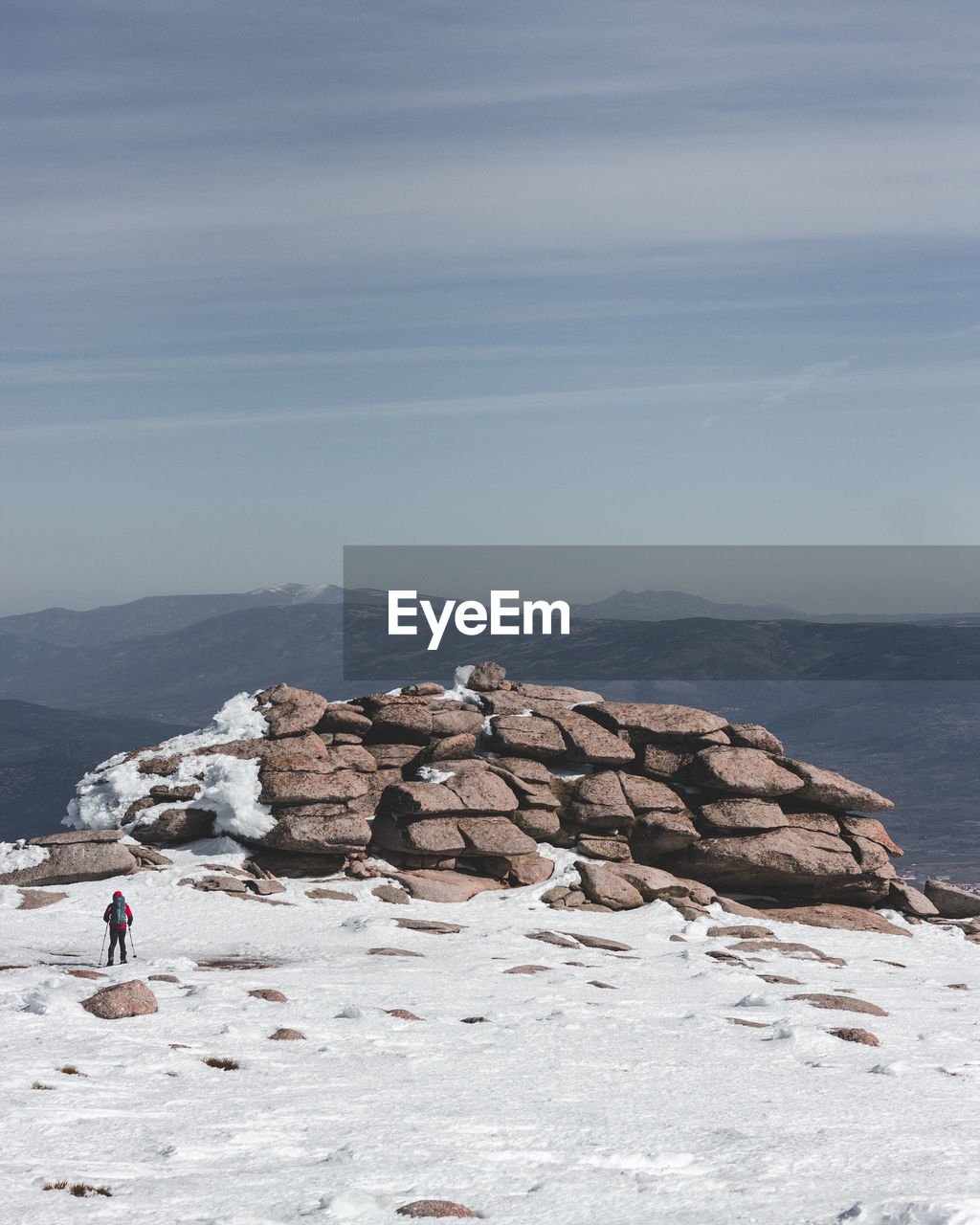 Distant view of hiker on snow covered mountain against sky