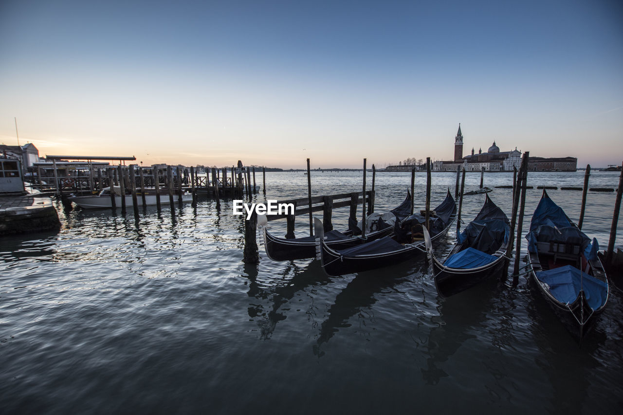 Gondola - traditional boat moored in san marco canal against sky during sunset