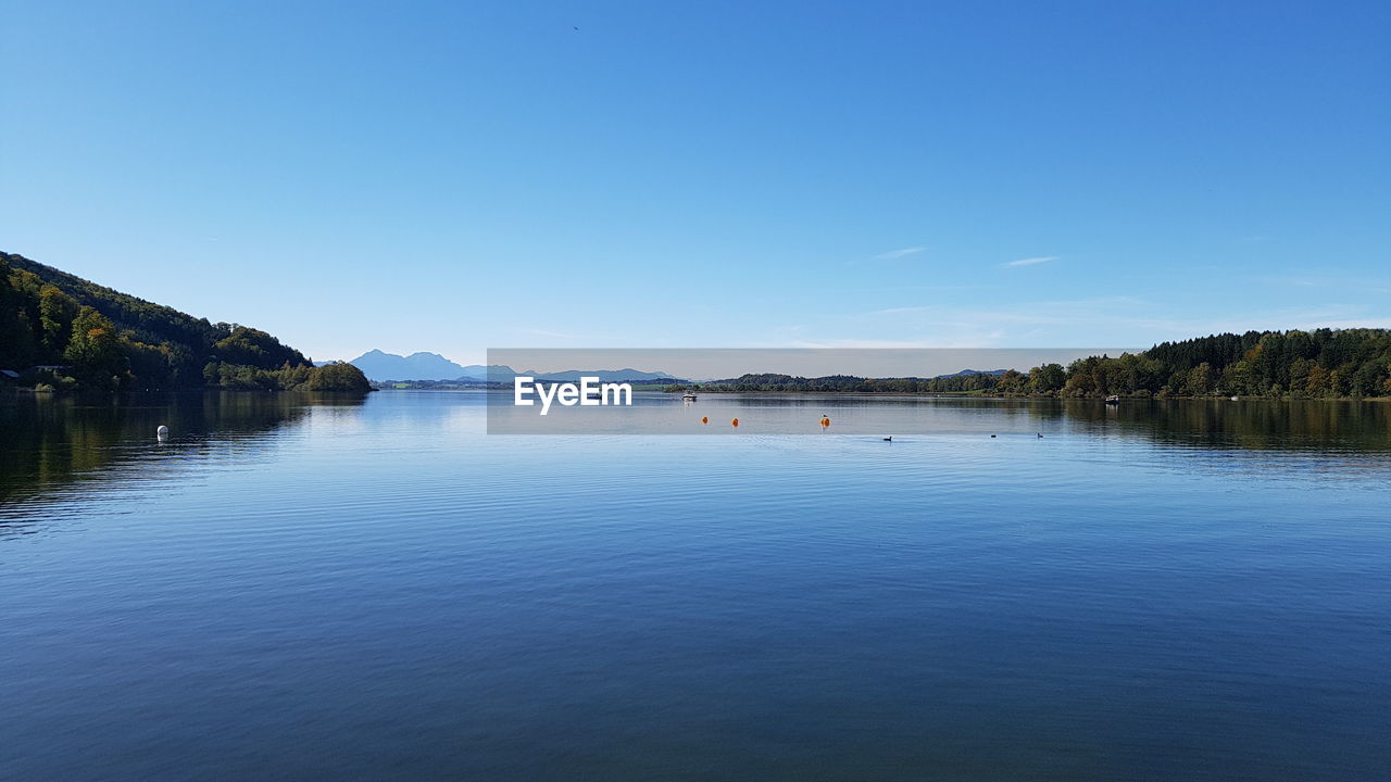 Scenic view of lake against clear blue sky