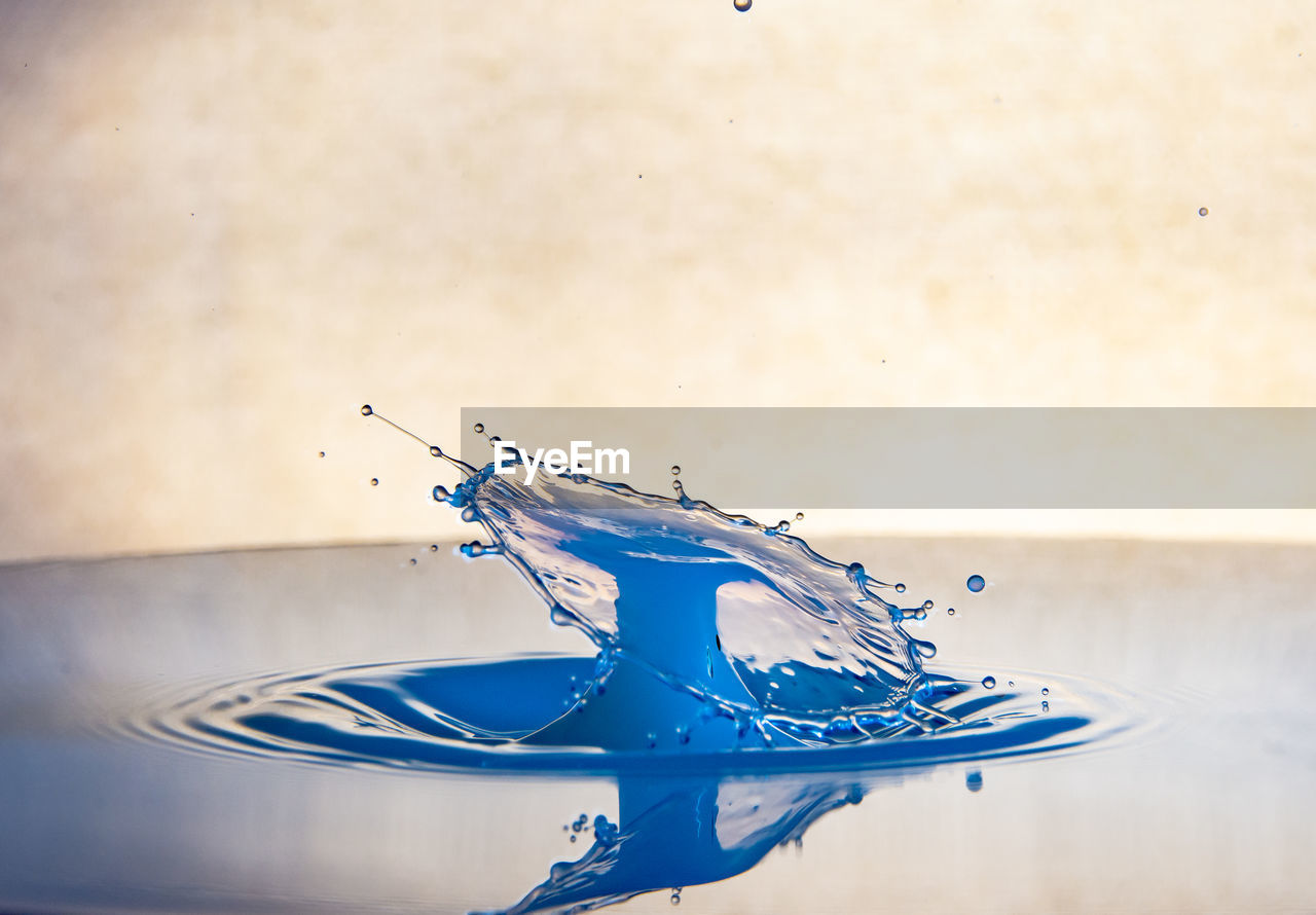 CLOSE-UP OF WATER DROP ON BLUE WALL