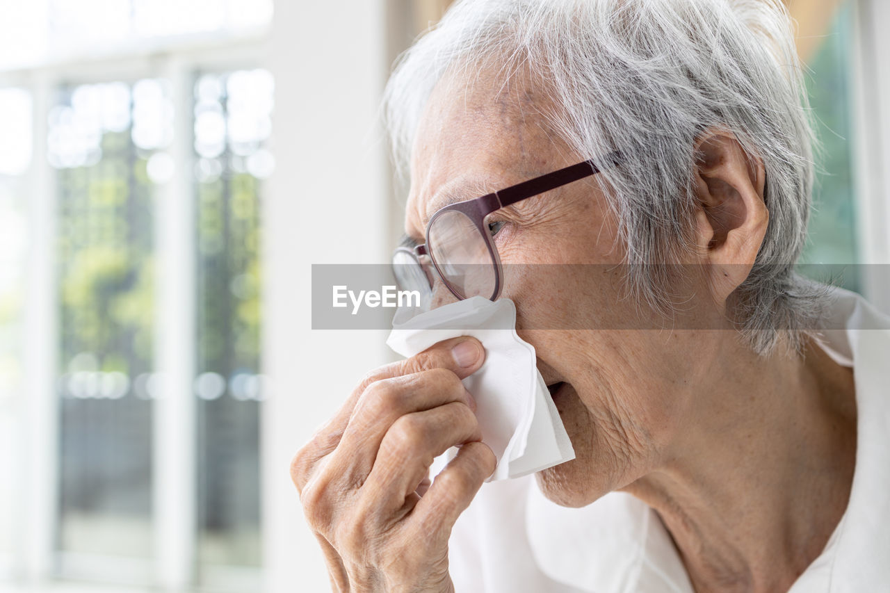 Senior woman blowing nose