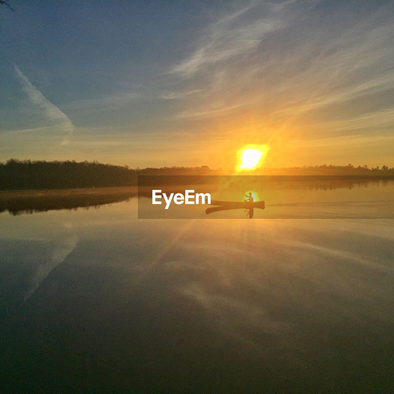 Person sailing on river against sky during sunset