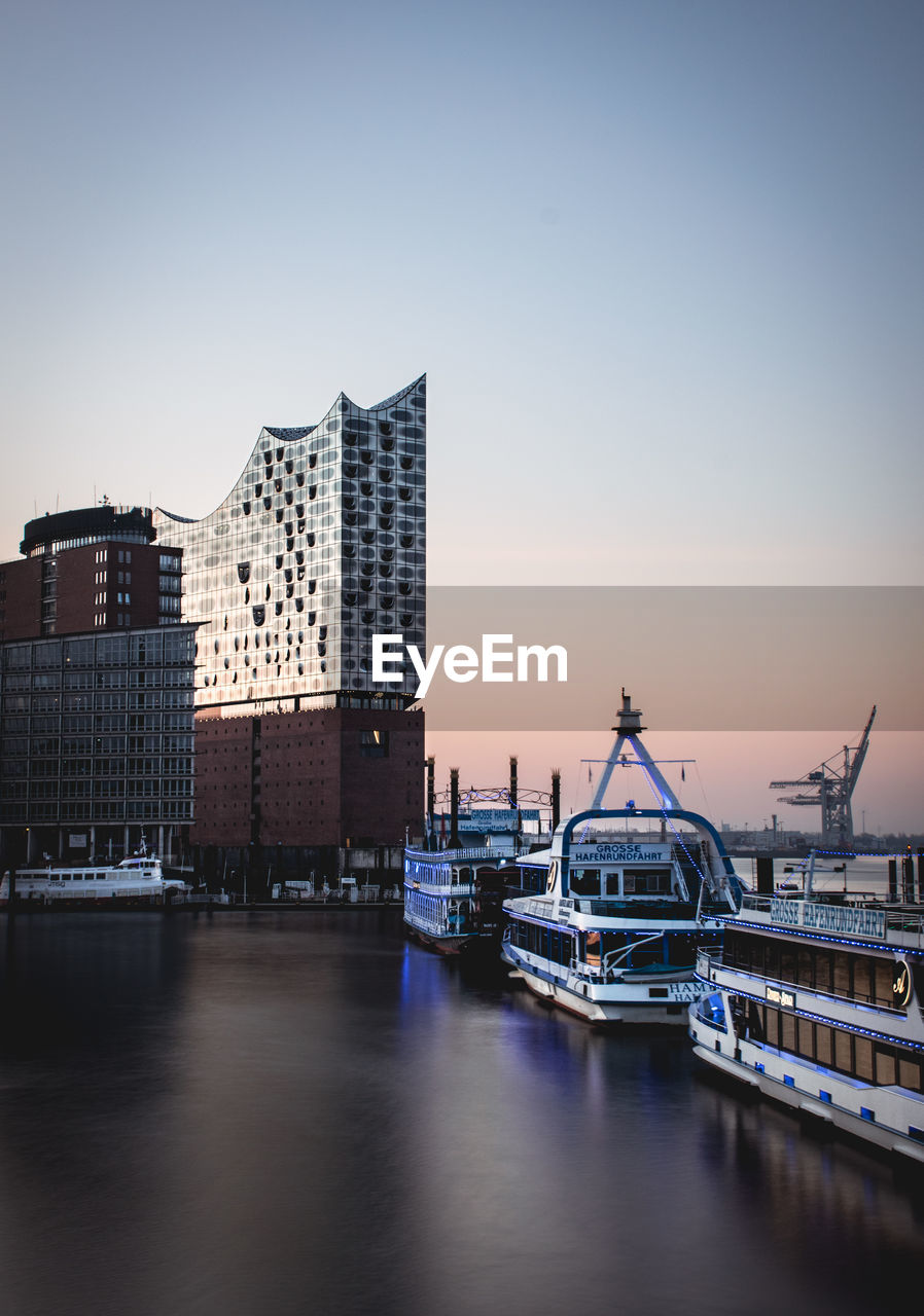 Boats moored at harbor against buildings in city