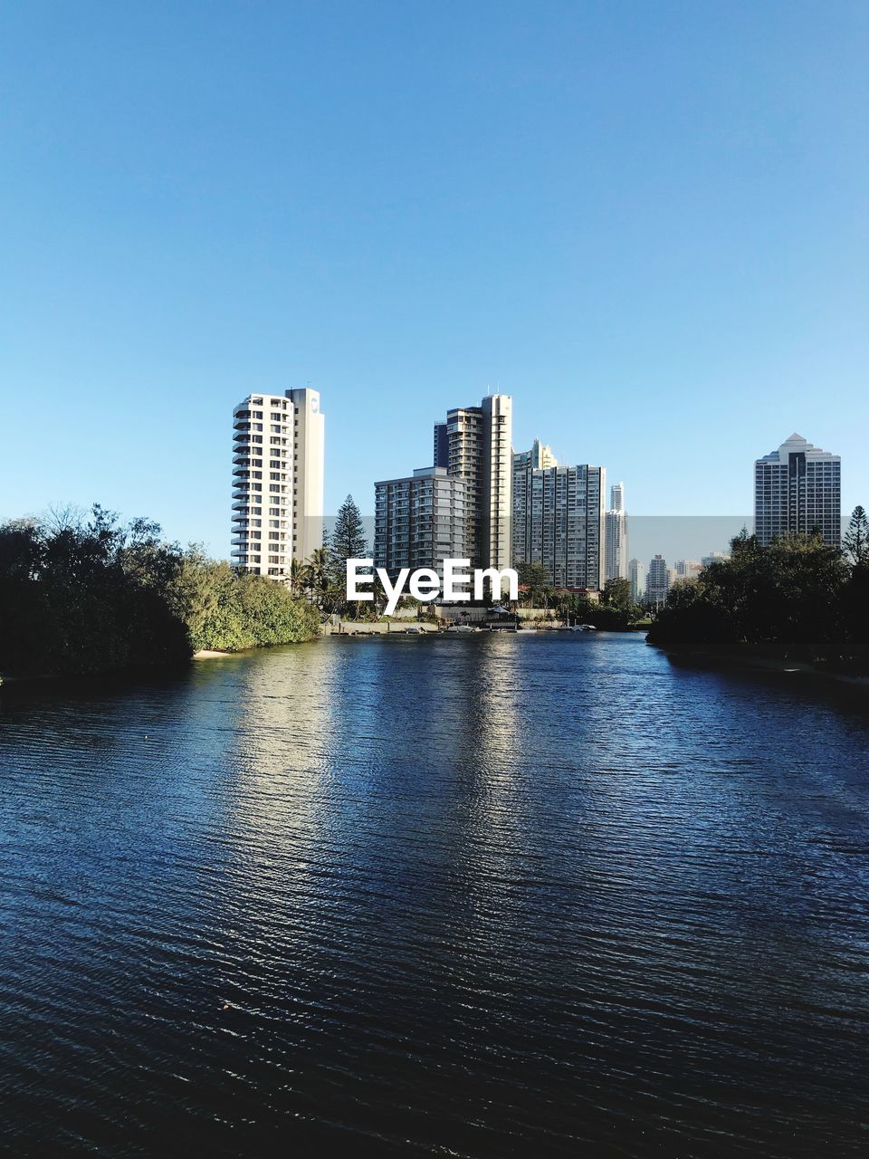 River by buildings in city against clear sky