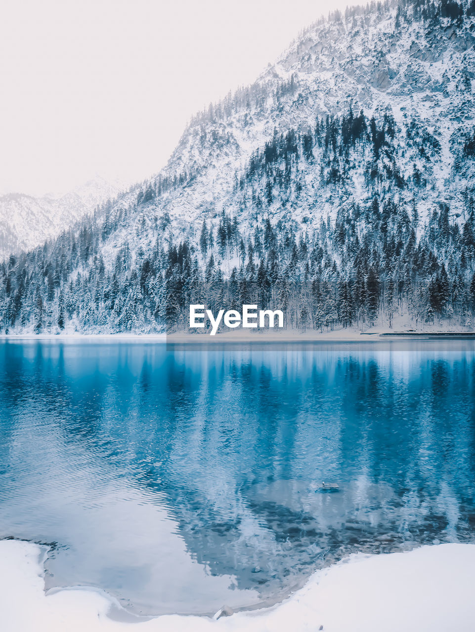 SCENIC VIEW OF LAKE AGAINST SNOWCAPPED MOUNTAINS DURING WINTER